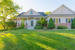 Neoclassical / greek revival house with brick siding, stucco siding, a front lawn, and a porch