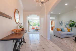 Entryway featuring ornamental molding, arched walkways, light colored carpet, light tile patterned floors, and recessed lighting