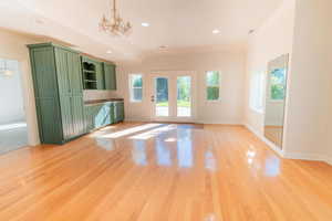 Unfurnished living room with a chandelier, crown molding, light wood-type flooring, and recessed lighting