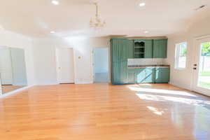Unfurnished living room with ornamental molding, light wood finished floors, a chandelier, and recessed lighting