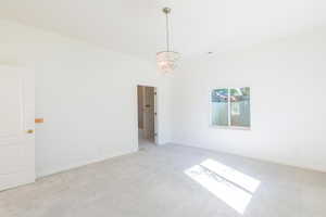 Unfurnished room featuring a chandelier and light colored carpet