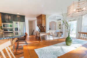 Dining room featuring arched walkways, light wood-style flooring, ceiling fan, and recessed lighting