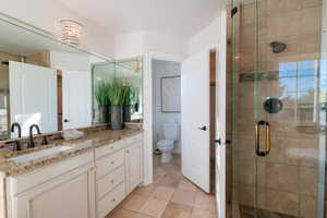 Bathroom featuring vanity, a stall shower, tile patterned flooring, and a chandelier