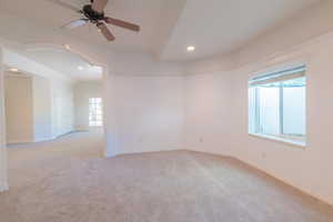 Unfurnished room featuring healthy amount of natural light, ceiling fan, light carpet, recessed lighting, and arched walkways