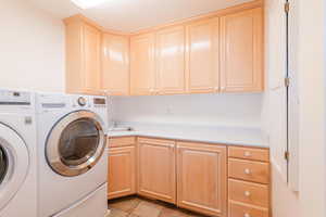 Laundry area with cabinet space, washing machine and clothes dryer, and light tile patterned floors