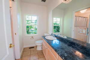 Bathroom with vanity, healthy amount of natural light, tile patterned floors, and a shower with curtain