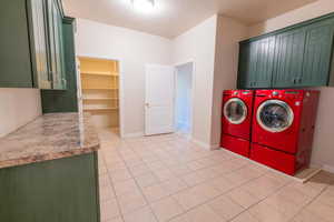Laundry area with cabinet space, washer and dryer, and light tile patterned flooring