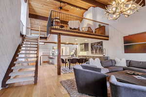 Living area with high vaulted ceiling, light wood-style floors, a chandelier, a wooden ceiling with exposed beams, and ceiling fan