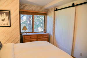 Bedroom with a barn door and wood walls