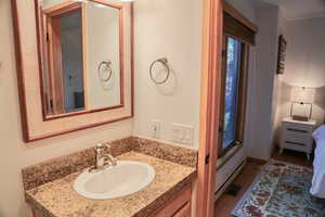 Bathroom with baseboard heating, vanity, and wood finished floors