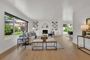 Living room featuring a brick fireplace, light wood-type flooring, and built in features