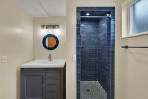 Bathroom featuring a tile shower and vanity