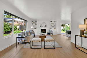 Living area with a fireplace, light wood-type flooring, and built in features