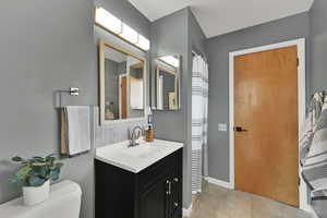 Bathroom with vanity, tile patterned floors, and tasteful backsplash