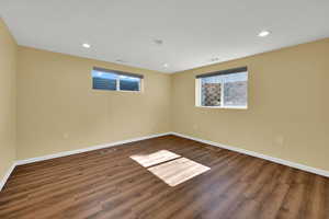 Empty room with healthy amount of natural light, dark wood-type flooring, and recessed lighting