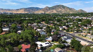 Aerial view of property and surrounding area featuring mountains and nearby suburban area
