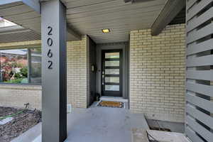 Property entrance featuring brick siding and a porch