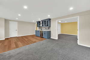 Indoor wet bar with backsplash, recessed lighting, wine cooler, and light wood finished floors