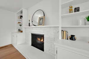 Detailed view of a stone fireplace, wood finished floors, and built in features