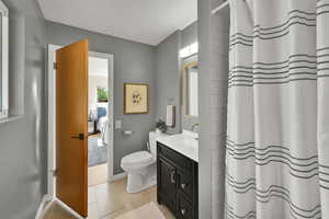 Ensuite bathroom with vanity, tile patterned flooring, and curtained shower