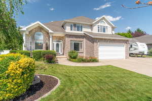 View of front facade with driveway, a garage, a front yard, brick siding, and a shingled roof