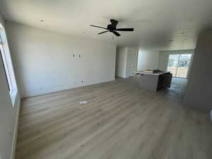 Unfurnished living room featuring light wood finished floors and a ceiling fan