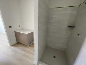 Bathroom featuring wood finished floors, vanity, and a tile shower
