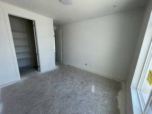 Unfurnished bedroom featuring a spacious closet and baseboards