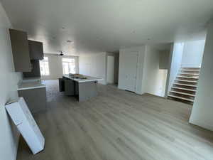 Unfurnished living room with light wood-style floors and stairs