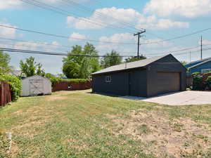 Fenced backyard featuring an outdoor structure and a garage