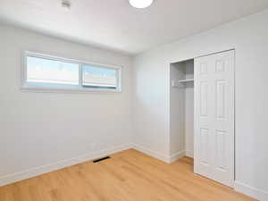 Unfurnished bedroom with light wood-type flooring, a closet, and a textured ceiling