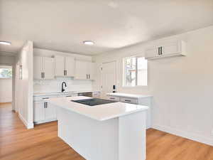 Kitchen with a center island, light wood-type flooring, white cabinets, and light countertops