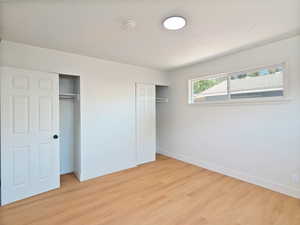 Unfurnished bedroom featuring multiple closets and light wood-style flooring