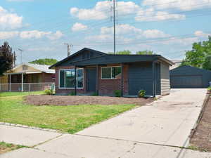 Ranch-style house with brick siding, a porch, an outbuilding, and a detached garage