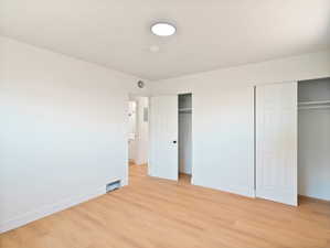 Unfurnished bedroom with two closets and light wood finished floors