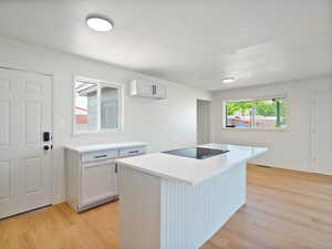 Kitchen featuring light wood-style floors, light countertops, white cabinetry, a center island, and a textured ceiling