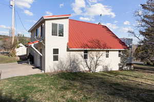 View of home's exterior with a yard, an outdoor structure, a metal roof, and concrete driveway
