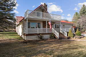 View of front of home featuring a porch, a front lawn, a garage, and a chimney