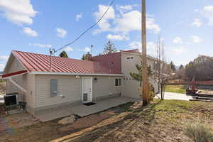 Rear view of house featuring a patio, a metal roof, and a chimney