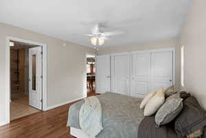 Bedroom featuring two closets, wood finished floors, a chandelier, and ceiling fan