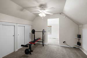 Exercise room with carpet flooring, vaulted ceiling, and a ceiling fan
