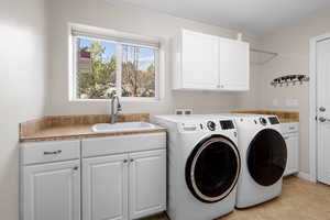 Laundry area featuring cabinet space, washer and clothes dryer, and light tile patterned flooring