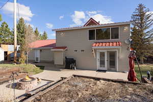 Rear view of property with a metal roof, an outdoor fire pit, and a patio