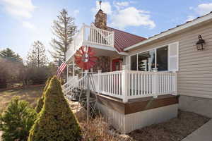 View of property exterior featuring a balcony, a metal roof, and a chimney