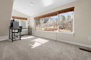 Carpeted home office with vaulted ceiling and baseboards