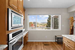 Kitchen featuring appliances with stainless steel finishes, plenty of natural light, a mountain view, and brown cabinets