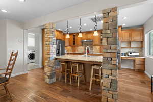 Kitchen with tasteful backsplash, ornate columns, open shelves, wood finished floors, and light stone countertops