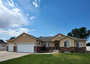 Ranch-style home featuring stucco siding, an attached garage, concrete driveway, and brick siding