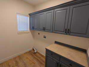Laundry area featuring cabinet space, electric dryer hookup, washer hookup, and light wood-type flooring