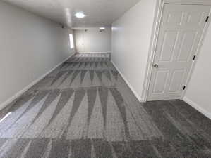 Hallway with carpet floors and a textured ceiling